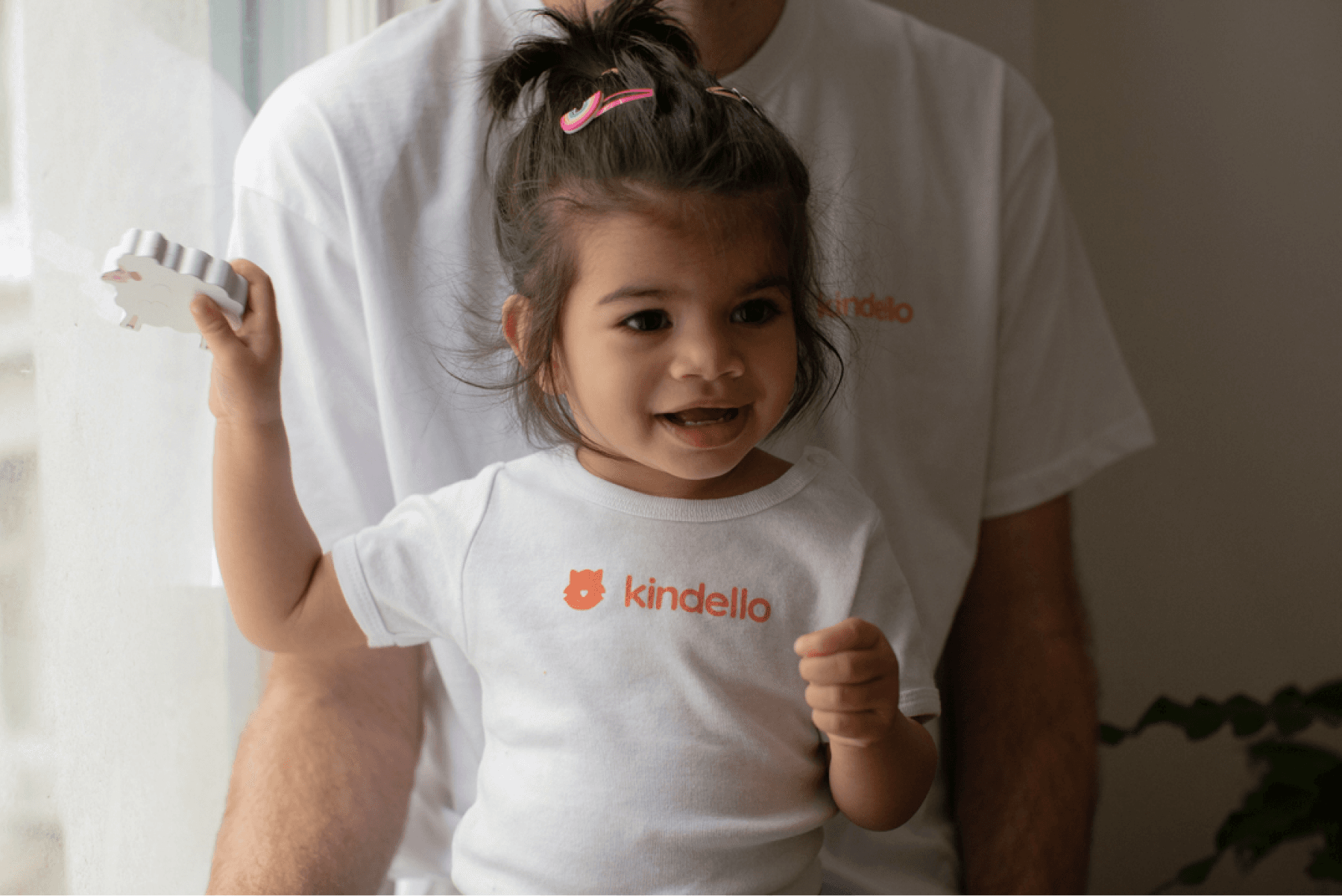 Toddler wearing Kindello onesie and playing with wooden toy