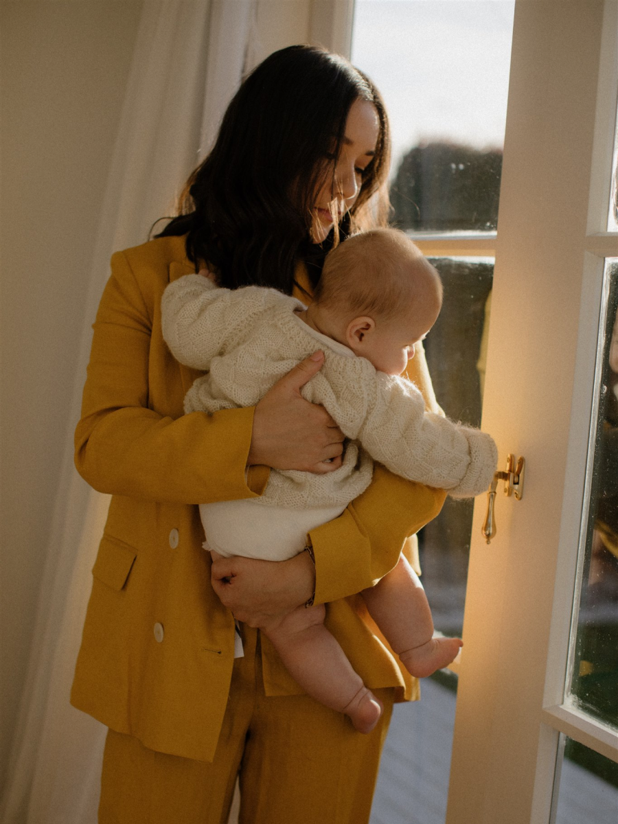 Mother holding baby wearing a yellow suit