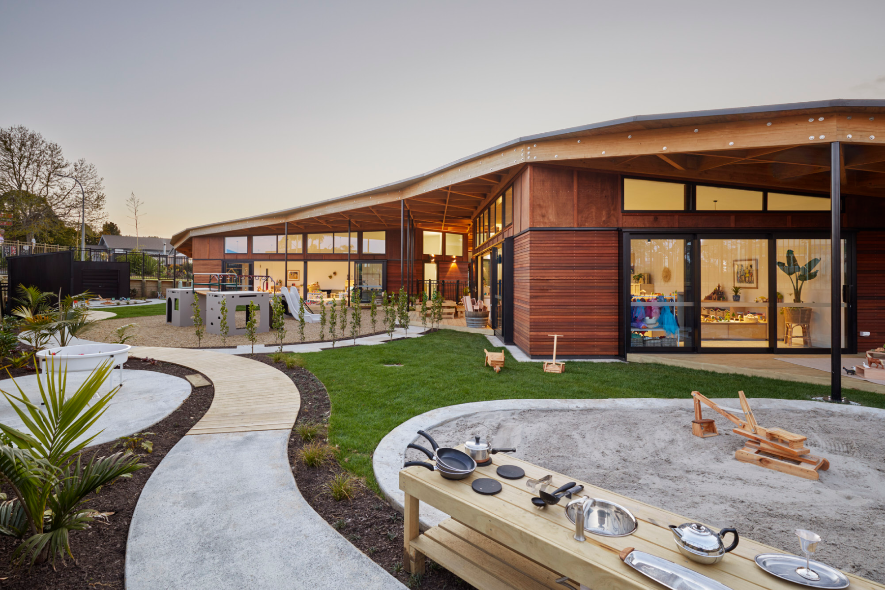 Wooden childcare centre with playground, sandpit, and sunset